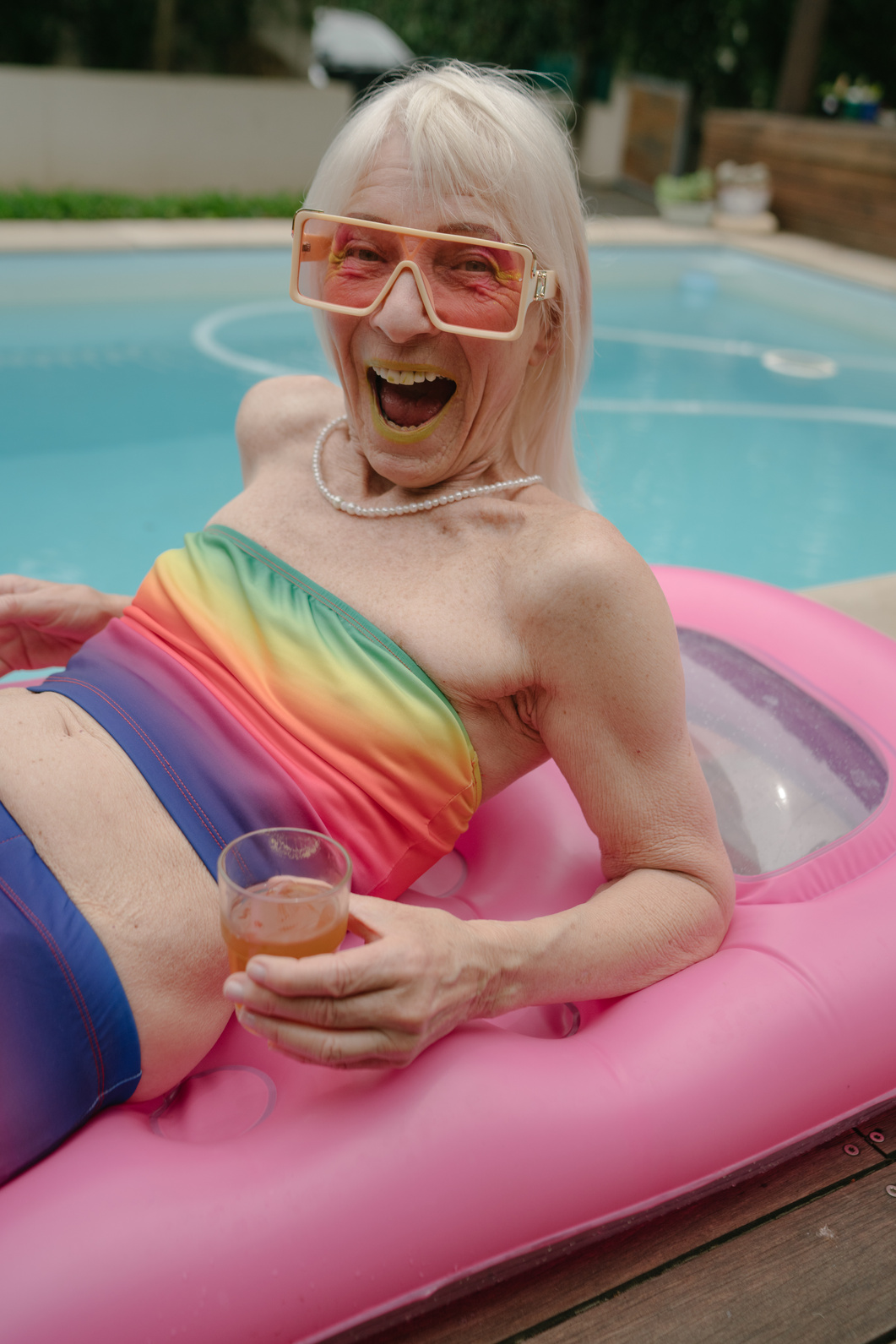 Happy Senior Woman in Colorful Outfit with Drink in Pool